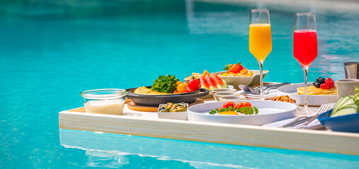 Breakfast in swimming pool, floating breakfast in luxurious tropical resort. Table relaxing on calm pool water, healthy breakfast and fruit plate by resort pool. Tropical couple beach luxury lifestyle
