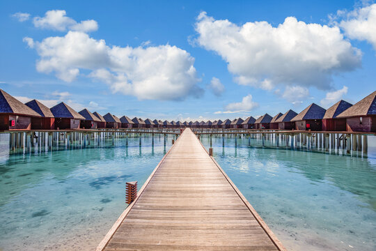 Amazing sunny landscape. Picturesque summer seaside in Maldives islands. Luxury resort villas seascape with wooden pier walkway. Dream beach symmetrical tropical lagoon bay, fantastic nature scenery