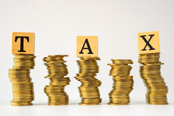 word tax in wooden blocks and stacked gold coins on white background