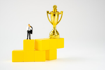 miniature businessman and Gold trophy  on winner yellow podium on white background
