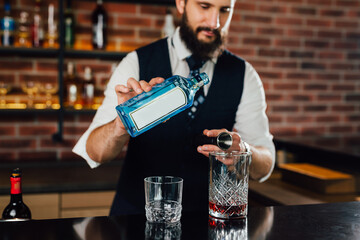 Bartender pours alcoholic drink into a cocktail mix