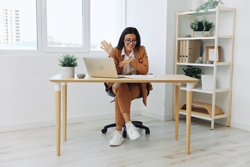 Business woman working in the office at her desk with a laptop, smile and business dialogue via video link, hand gestures in dialogue, online internet