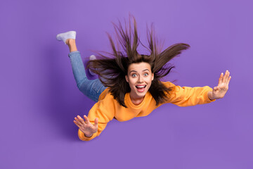 Full length photo of cheerful pretty lady rejoice can fly halloween party wear orange trendy sweater isolated on purple color background