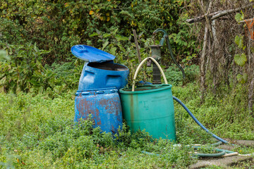 garden artwork in allotment of rain barrels, buckets and a pump