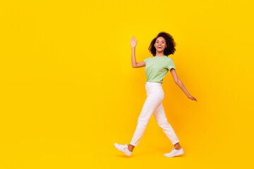 Fototapeta na wymiar Full body size attractive adorable gorgeous nice woman wear green t-shirt white pants showing hello palm positive isolated on yellow color background