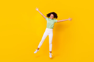 Fototapeta na wymiar Full length photo of young gorgeous nice pretty girl wear casual clothes beaming palms up jump dance celebrate party weekend isolated on yellow color background