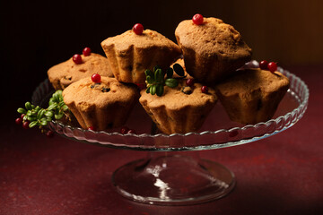 cupcakes with fresh lingonberries on a glass dessert stand on a dark background