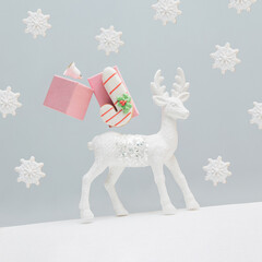 Winter Xmas greeting card with white cute reindeer, candy cane cookie, bell and pink gift boxes on isolated gray background with snowflakes. New Year holiday decoration concept. Christmas symbols.