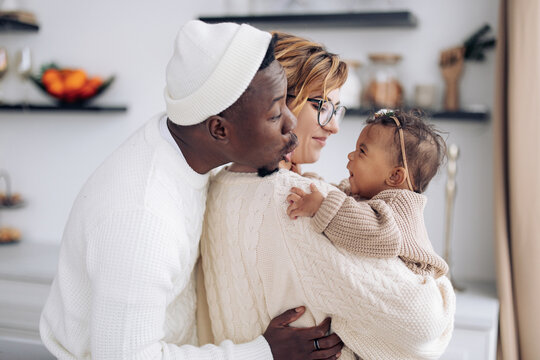 Happy interracial family has fun and plays with their baby daughter