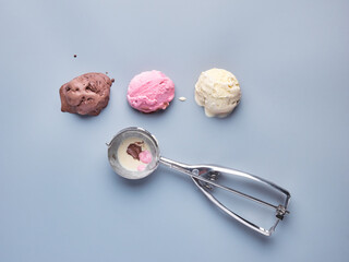 strawberry, chocolate and vanilla ice cream scoops and a metallic scoop isolated on a light background