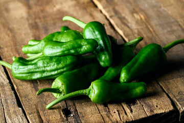 A bunch of green Padron peppers isolated on a wooden table
