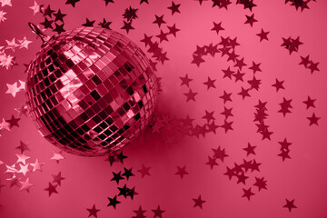 Shiny disco ball with rays on viva magenta background. Creative party background with copy space. Happy New Year. Trending color of 2023 - Viva Magenta.