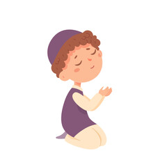 Jewish boy praying, little kid in ethnic clothes from Israel sitting on knees to pray