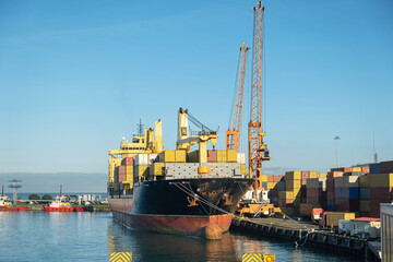 Container ship in container port with cranes loading containers from the ship. Logistic, export concept