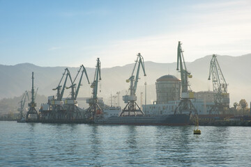Batumi sea port with cranes silhouettes, ships, ferries at sunrise. Logistic, industry, shipping, concept