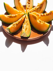 Slices of melon on a round plate, white background, with copy space