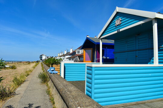 Beach huts made from solid wood freshly painted in bright colours decorated with crab fish and shells right on the beach side promenade in the charming coastal Whitstable town attracting many families