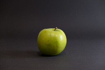 A Whole and a slice of apple on a black background, side view, Green apples, fresh, isolated on black, sliced apple on a stick