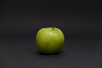 A Whole and a slice of apple on a black background, side view, Green apples, fresh, isolated on black, sliced apple on a stick