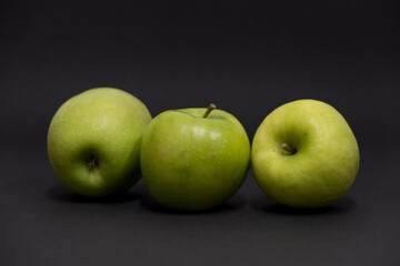 A Whole and a slice of apple on a black background, side view, Green apples, fresh, isolated on black, sliced apple on a stick