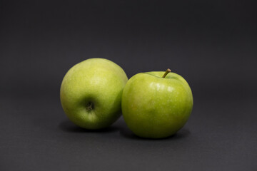 A Whole and a slice of apple on a black background, side view, Green apples, fresh, isolated on black, sliced apple on a stick