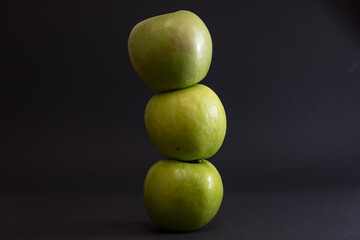 A Whole and a slice of apple on a black background, side view, Green apples, fresh, isolated on black, sliced apple on a stick