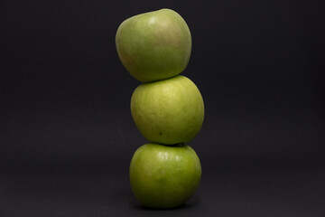A Whole and a slice of apple on a black background, side view, Green apples, fresh, isolated on black, sliced apple on a stick