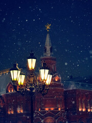 Street lantern and old city towers in winter snowy night, abstract background. Christmas and new year holidays. festive winter season