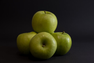 A Whole and a slice of apple on a black background, side view, Green apples, fresh, isolated on black, sliced apple on a stick