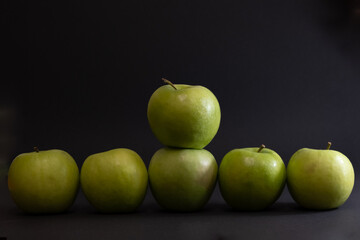 A Whole and a slice of apple on a black background, side view, Green apples, fresh, isolated on black, sliced apple on a stick
