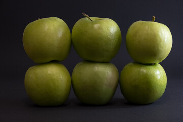 A Whole and a slice of apple on a black background, side view, Green apples, fresh, isolated on black, sliced apple on a stick