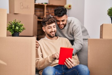 Young couple using touchpad sitting on sofa at new home