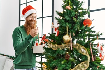 Young redhead man smiling confident decorating christmas tree at home