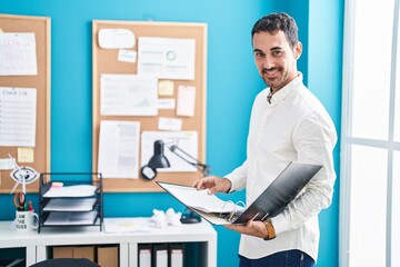 Young hispanic man business worker reading document at office