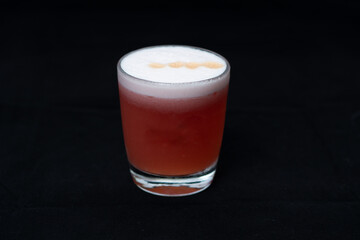 pisco sour de frutos rojos en fondo negro en barra de bar