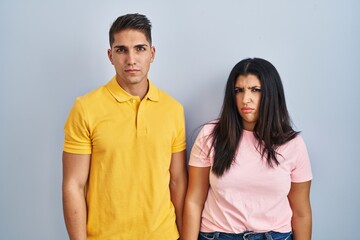 Young couple standing over isolated background skeptic and nervous, frowning upset because of problem. negative person.