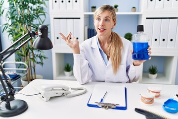 Obraz na płótnie Canvas Young blonde woman wearing dentist uniform holding mouthwash at clinic