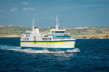 Fototapeta na wymiar Ferry traveling on the gozo malta channel line between the city of Mgarr and Cirkewwa on rough waters on a sunny day.