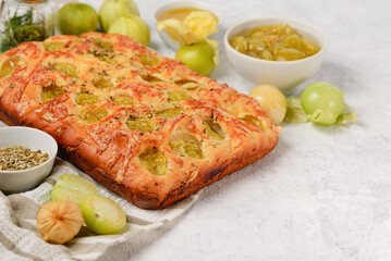 Traditional Italian focaccia bread with physalis, dried herbs and cheese. Fruit pie in a baking dish on a white background