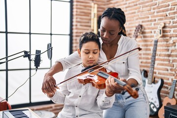 African american mother and son student learning play violin at music studio © Krakenimages.com