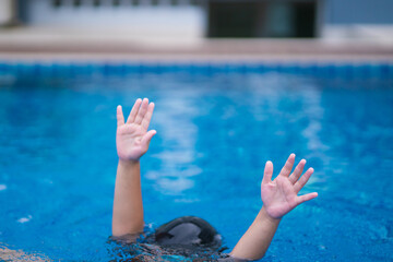 child in danger drowning in the pool,  kid girl cannot swim to deep water and raise two hand for...