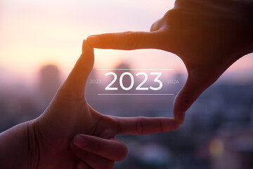 2023 new year celebration concept.Silhouette of Photo sign made by human hands on blurred sunset...