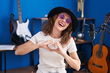 Young woman artist doing heart gesture with hands at music studio