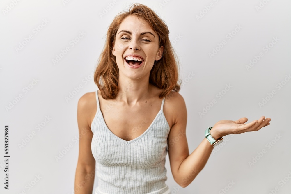 Sticker Beautiful caucasian woman standing over isolated background smiling cheerful presenting and pointing with palm of hand looking at the camera.