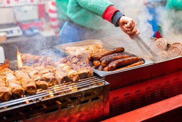vendor fries meat and sausage on the grill in the city center at the Christmas market in Gdansk...