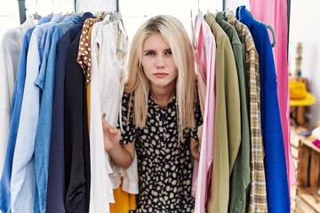 Naklejka na ściany i meble Young blonde woman searching clothes on clothing rack depressed and worry for distress, crying angry and afraid. sad expression.