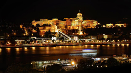 Fototapeta na wymiar Night shot, long exposure photography, famous historical Buda Castle in illuminated at night, Royal Palace view by the Danube river, Budapest, Hungary