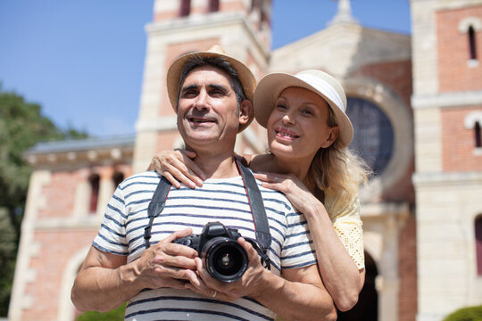a middle-aged couple standing taking photographs on their camera