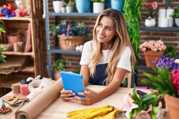 Young blonde woman florist smiling confident using touchpad at florist