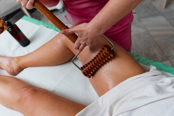 Young woman having leg massage with rollers in beauty spa salon, close up